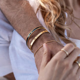 Close-up of a person's arm with multiple gold bracelets and rings.