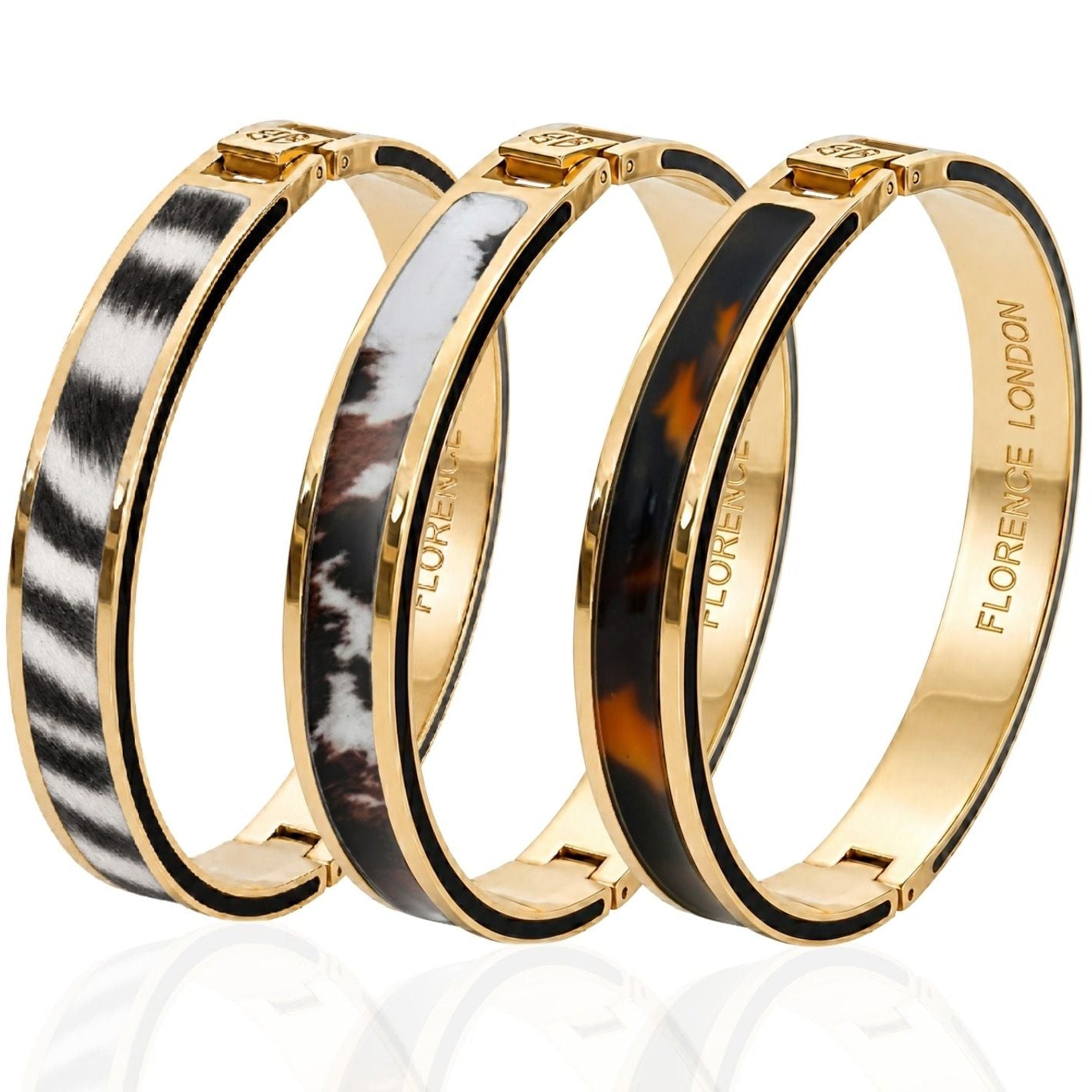 Three gold-tone bangle bracelets with inlay patterns, displayed on a reflective white surface. The bracelets feature zebra print, marbled black and white, and tortoiseshell inlay designs, with 'FLORENCE LONDON' engraved on the inside.